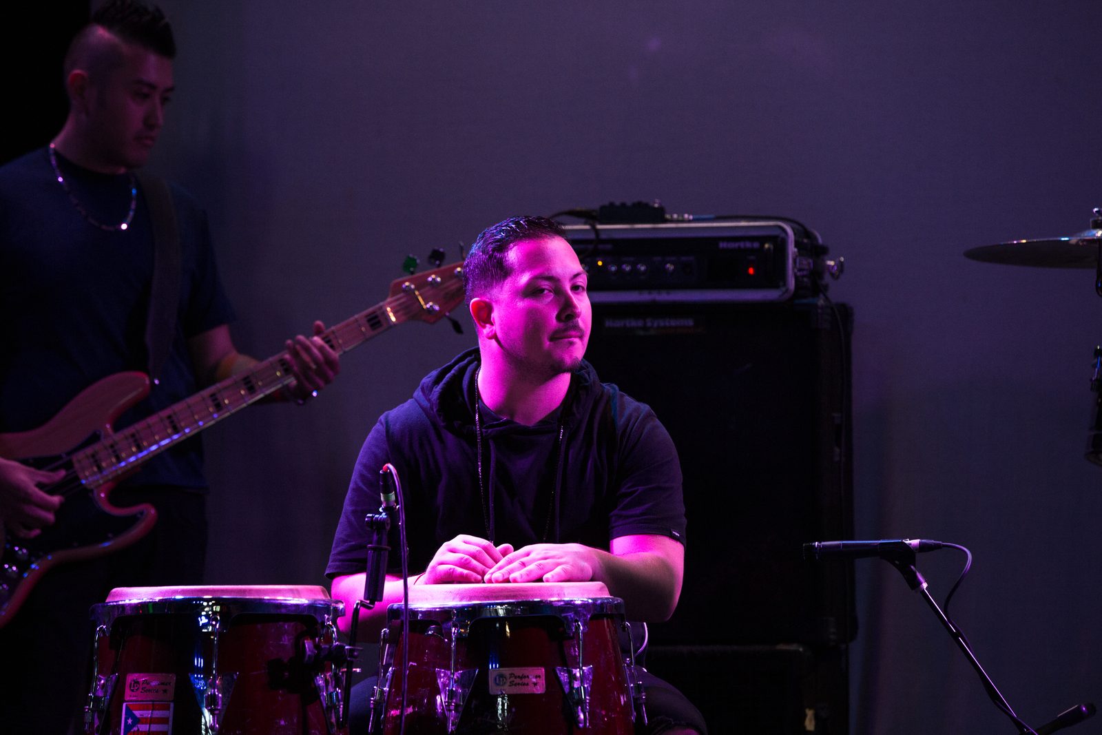 La Obra performing live: congas and guitar